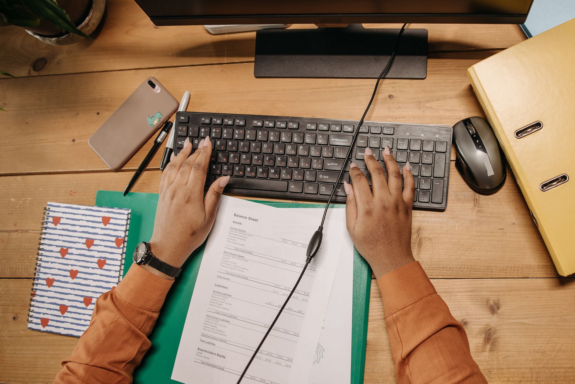 Mains sur un clavier avec des documents de facturation à côté