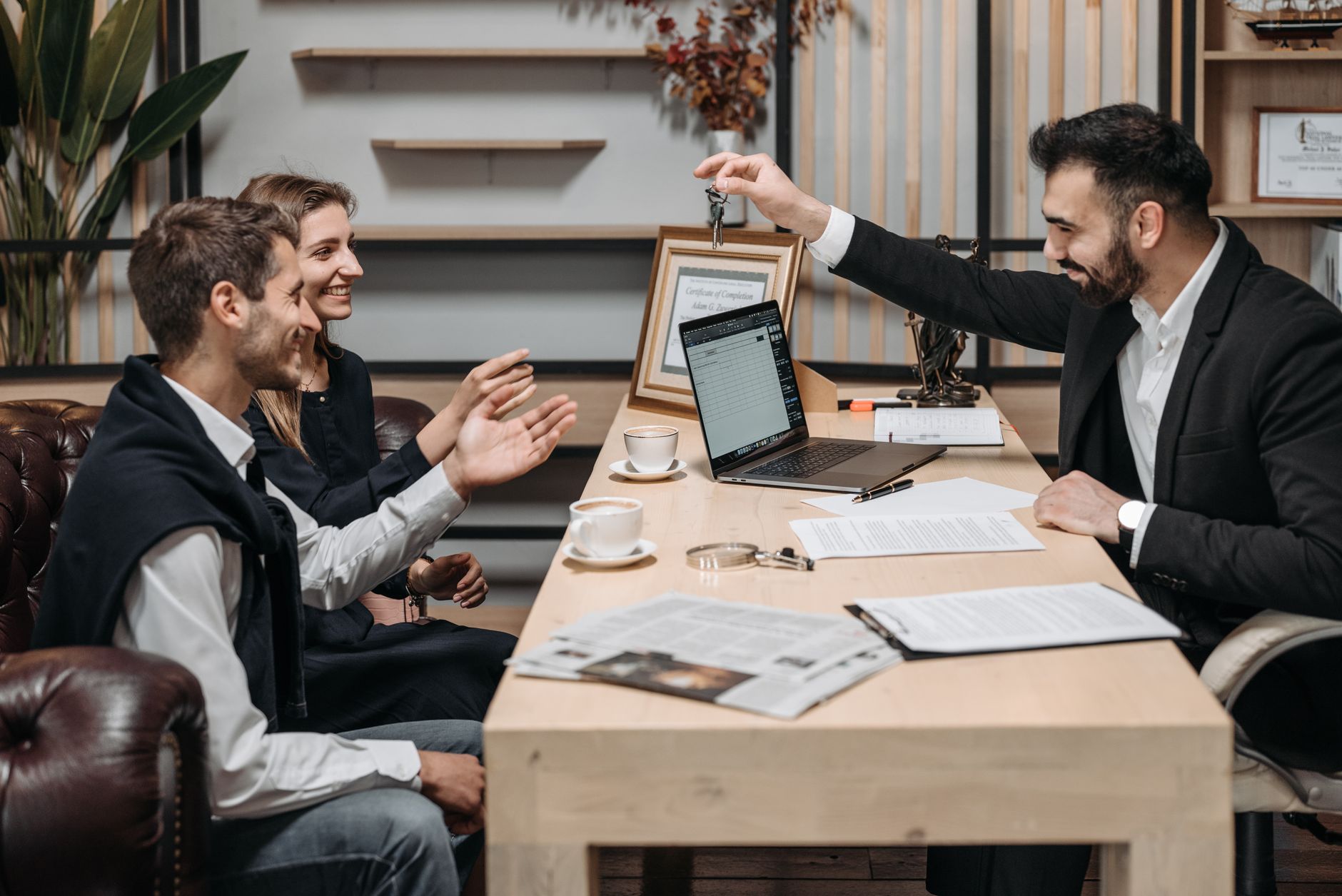 Agent immobilier qui échange avec un client professionnel, dossier de transaction ouvert sur le bureau